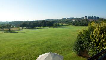 Vista de un campo de golf con un paraguas grande al frente.