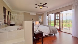 Un dormitorio amplio con una cama grande, un vestidor, una bañera y un balcón con vistas.