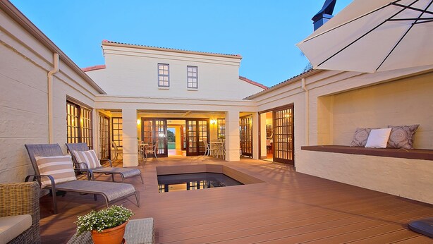 Amplio patio exterior con piscina, zonas de estar y acceso al edificio.