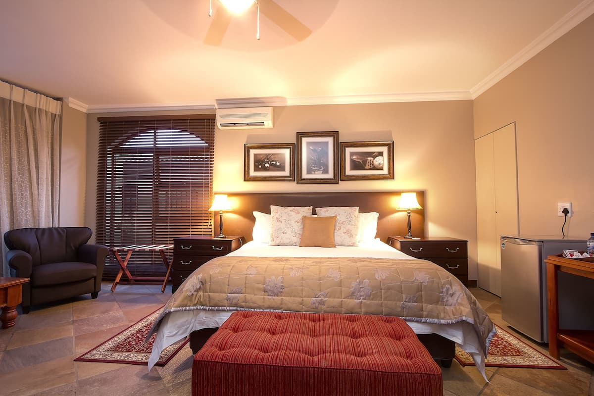 A bedroom with a bed, bedside tables, a chair, a desk, and a wardrobe.