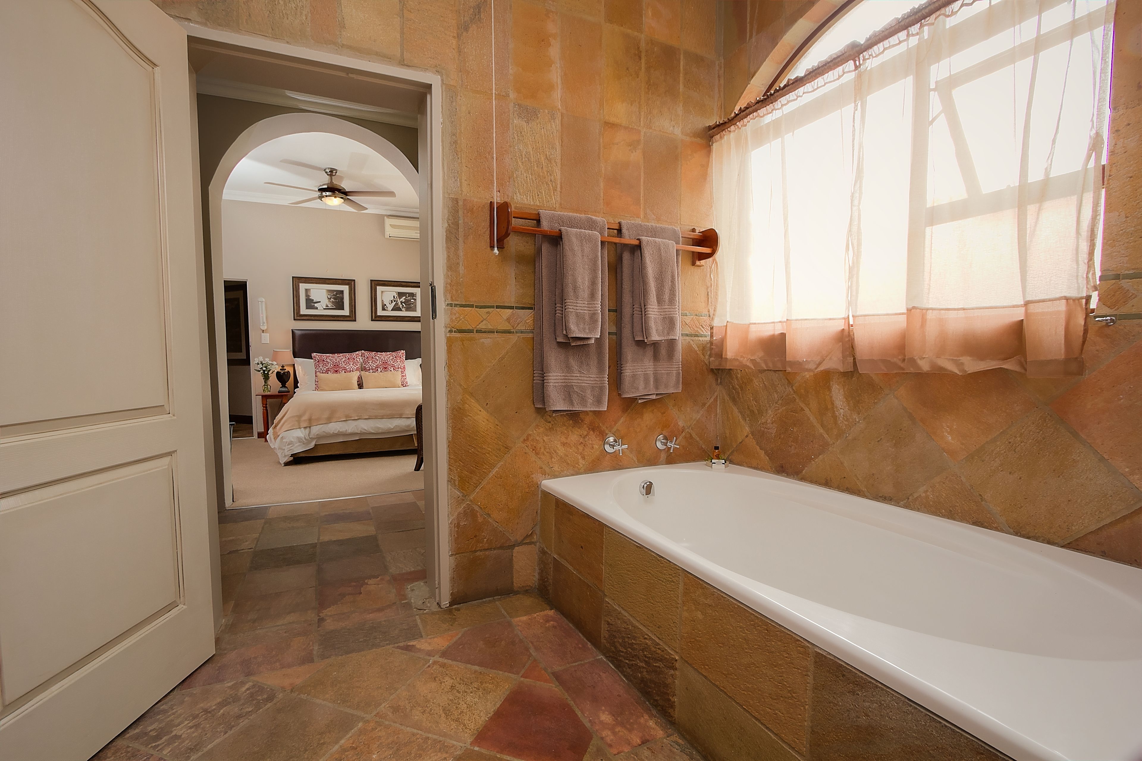 A bathroom with a bathtub, a shower, and a vanity. There is a towel rack with towels hanging on it.