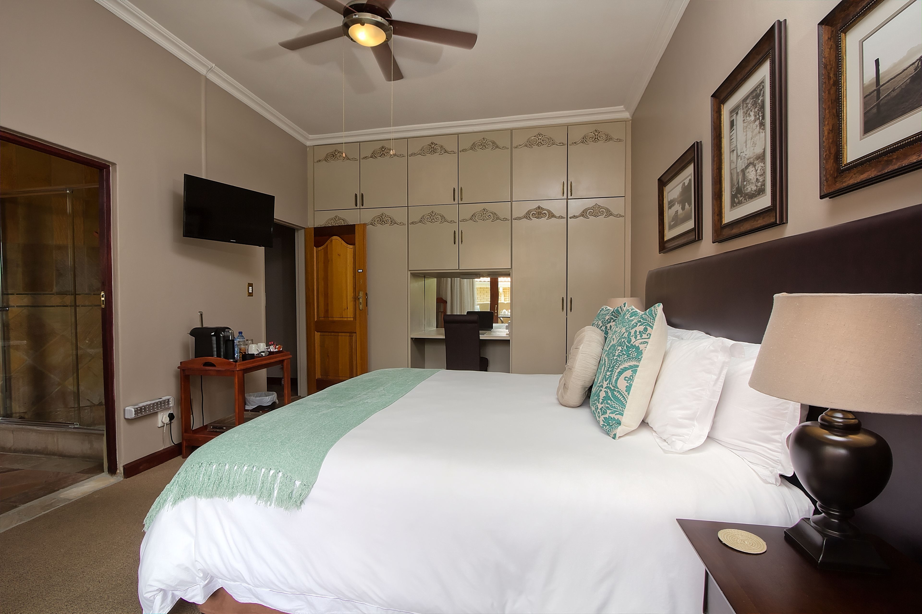 A hotel room with a bed, a desk, a television, and a wardrobe.