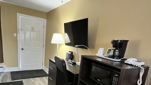 A compact hotel room with a desk, chair, flat-screen TV, coffee maker, microwave, and a telephone. - Travellers Inn Pembroke (Pembroke)