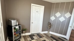 A hallway with a refrigerator stocked with beverages, a door labeled "PRIVATE," and a patterned rug. - Travellers Inn Pembroke (Pembroke)