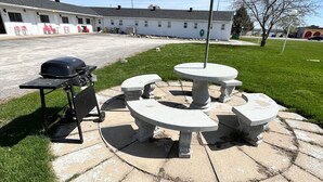 A patio area with a barbecue grill and a stone table. - Travellers Inn Pembroke (Pembroke)