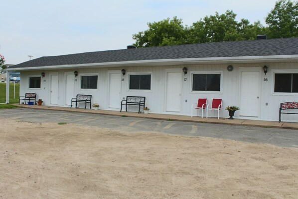 A motel with numbered doors, outdoor seating, and a parking lot.