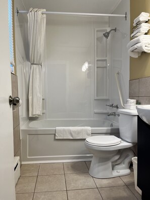 Bathroom features a shower enclosure, bathtub, and toilet, with a towel rack and sink.