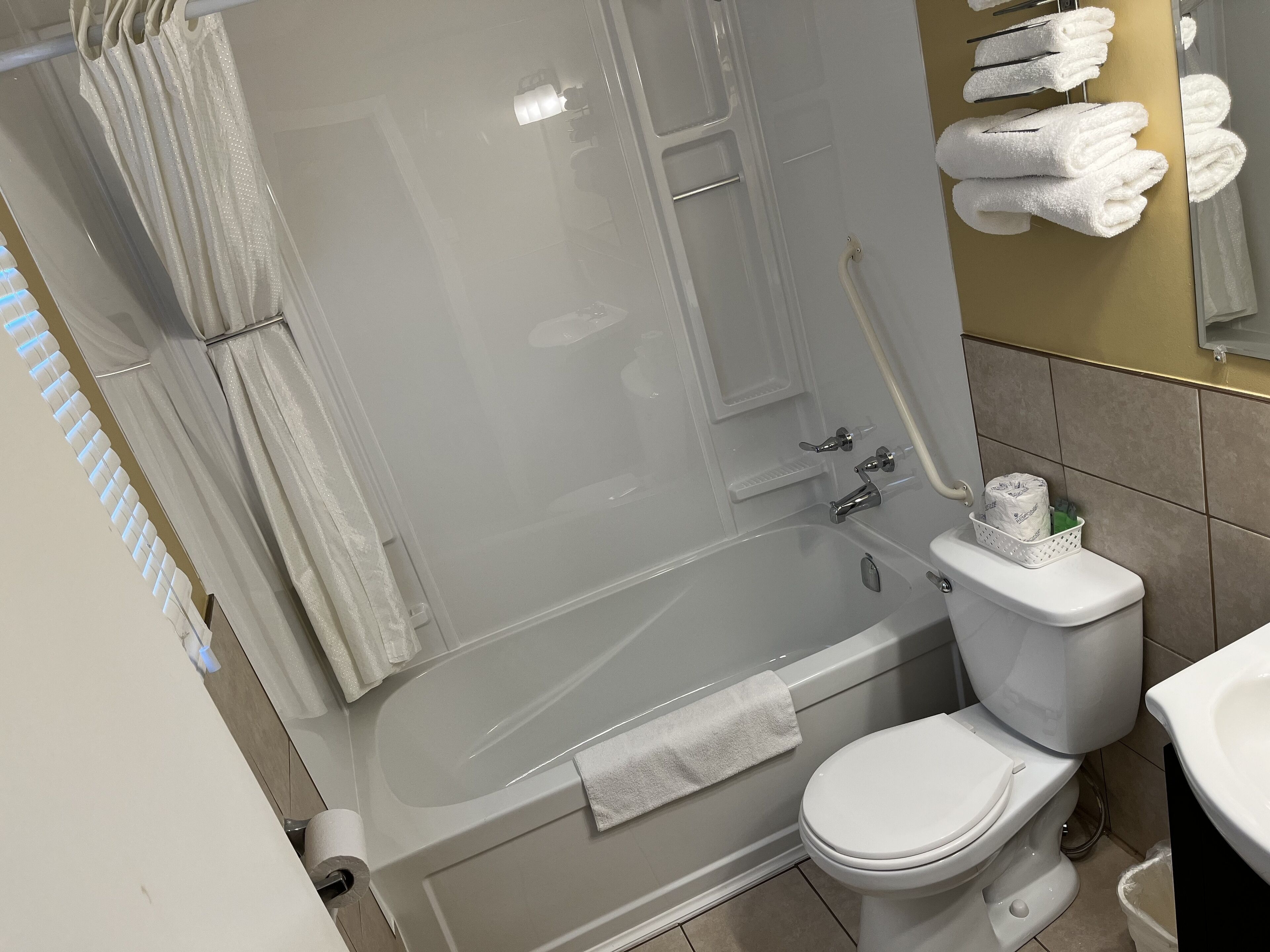 A bathroom with a bathtub, toilet, and a towel rack with towels.
