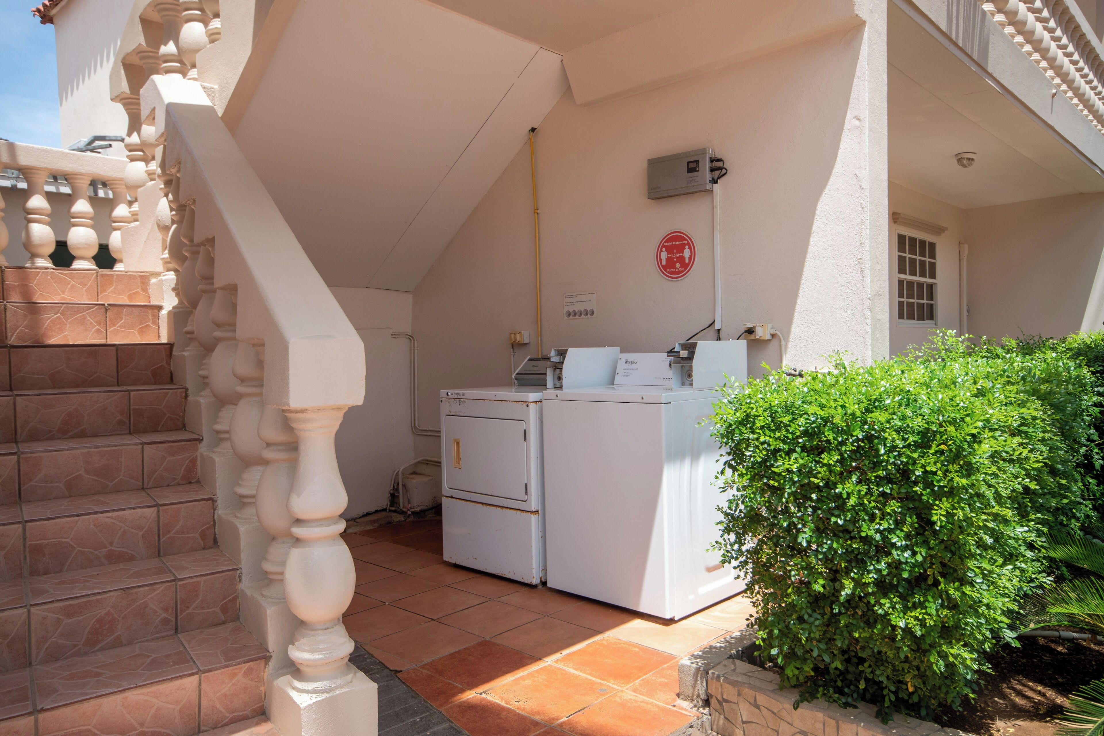 A laundry area with a washing machine and dryer, a staircase with a balustrade, and a small window.