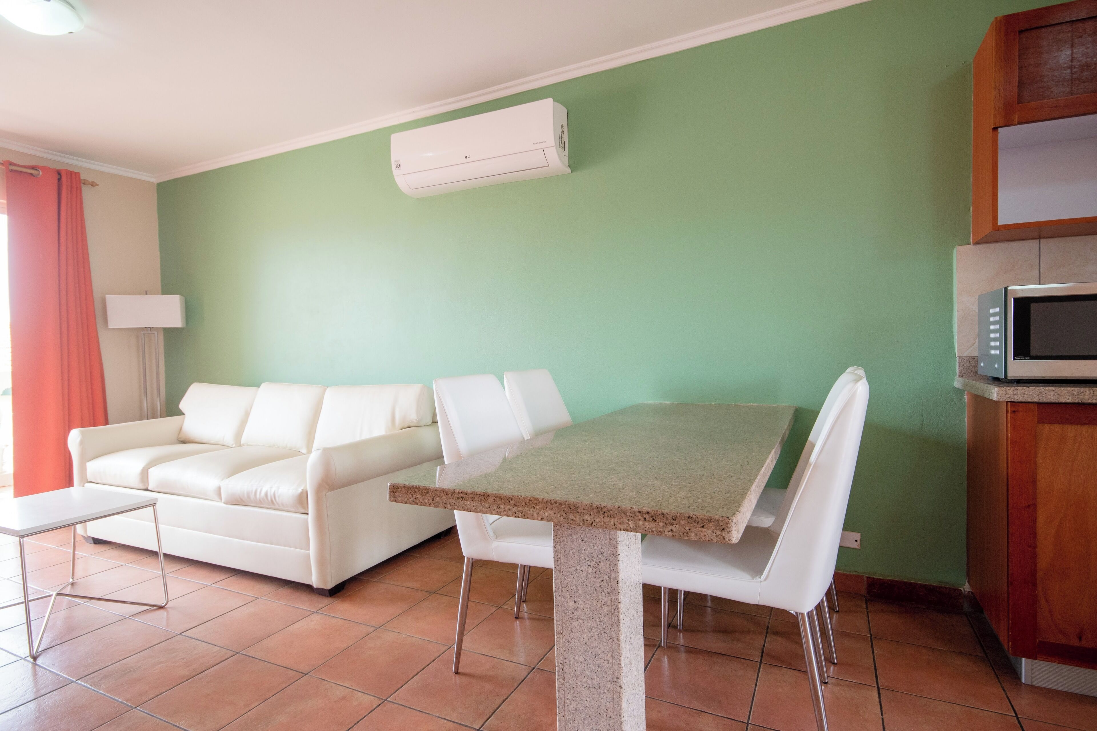 A compact living space with a dining table, white sofa, and a microwave.