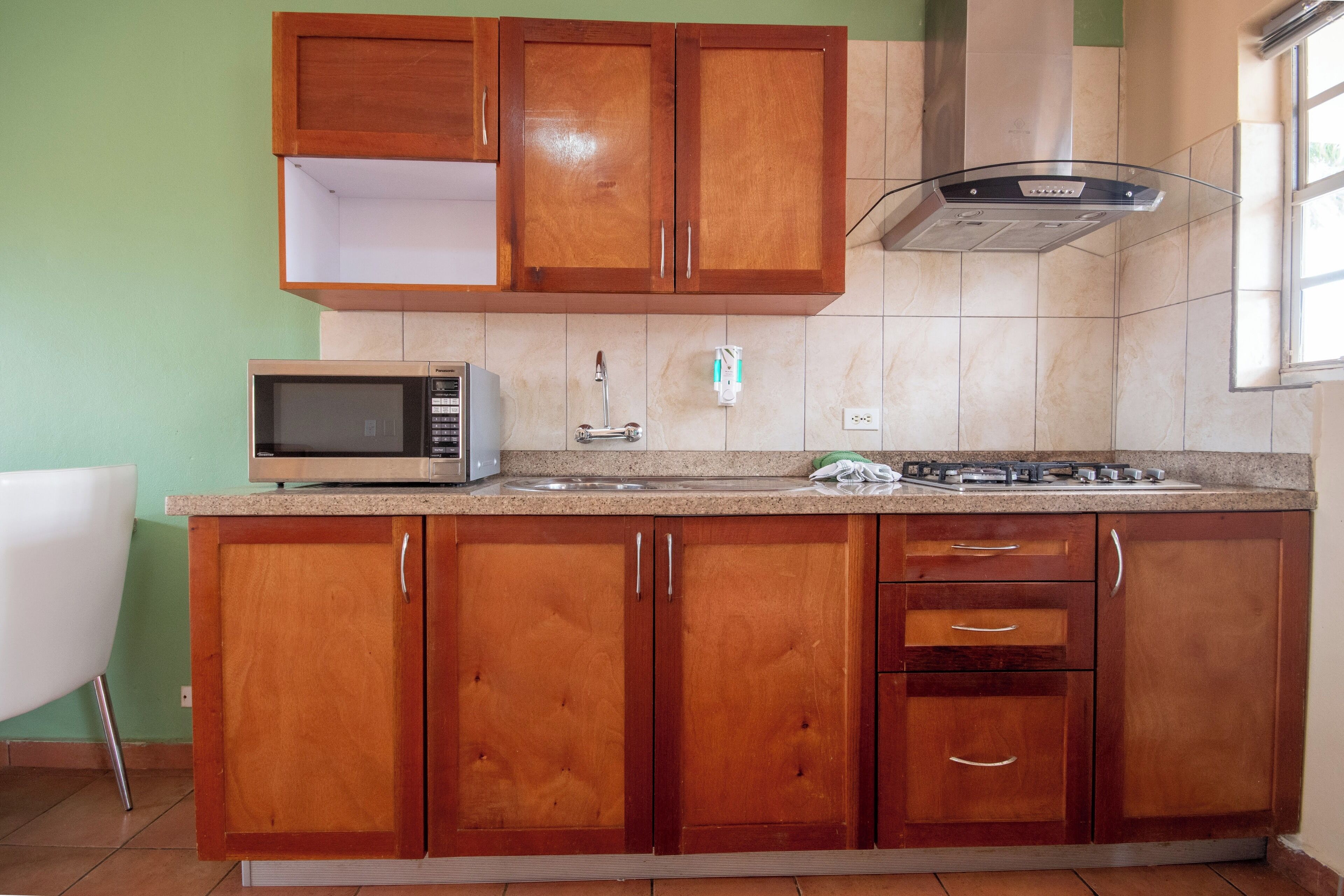 A kitchen with wooden cabinets, a microwave, a gas stove, and a window.