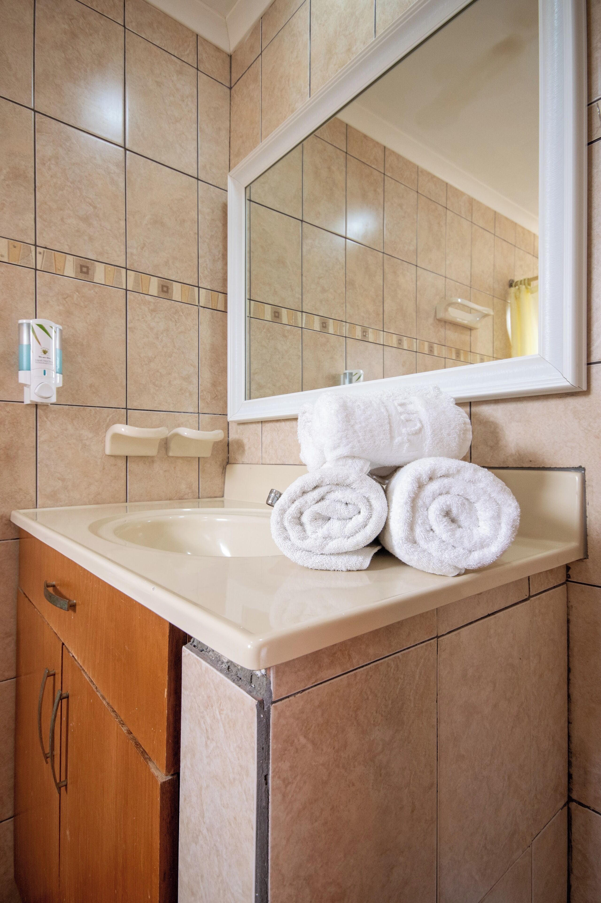 A bathroom with a sink, mirror, and stacked towels.