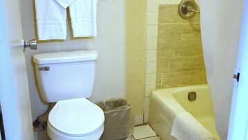 Un baño con inodoro, cubo de basura y bañera.