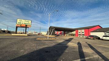 A parking lot with a River Valley Inn & Suites sign, a red building, and a few cars parked.