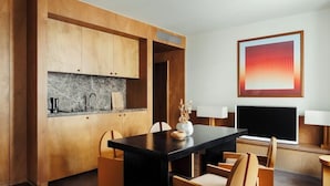 A modern kitchen with wooden cabinetry, a marble backsplash, and a black dining table. - Palace Hotel (Paris)