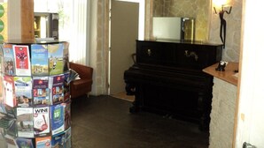 A cozy living room with a stone wall, a piano, and a stack of magazines. - Palace Hotel (Paris)