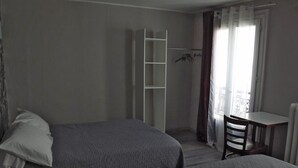 A bedroom with two beds, a desk, a chair, a wardrobe, and a window with curtains. - Palace Hotel (Paris)