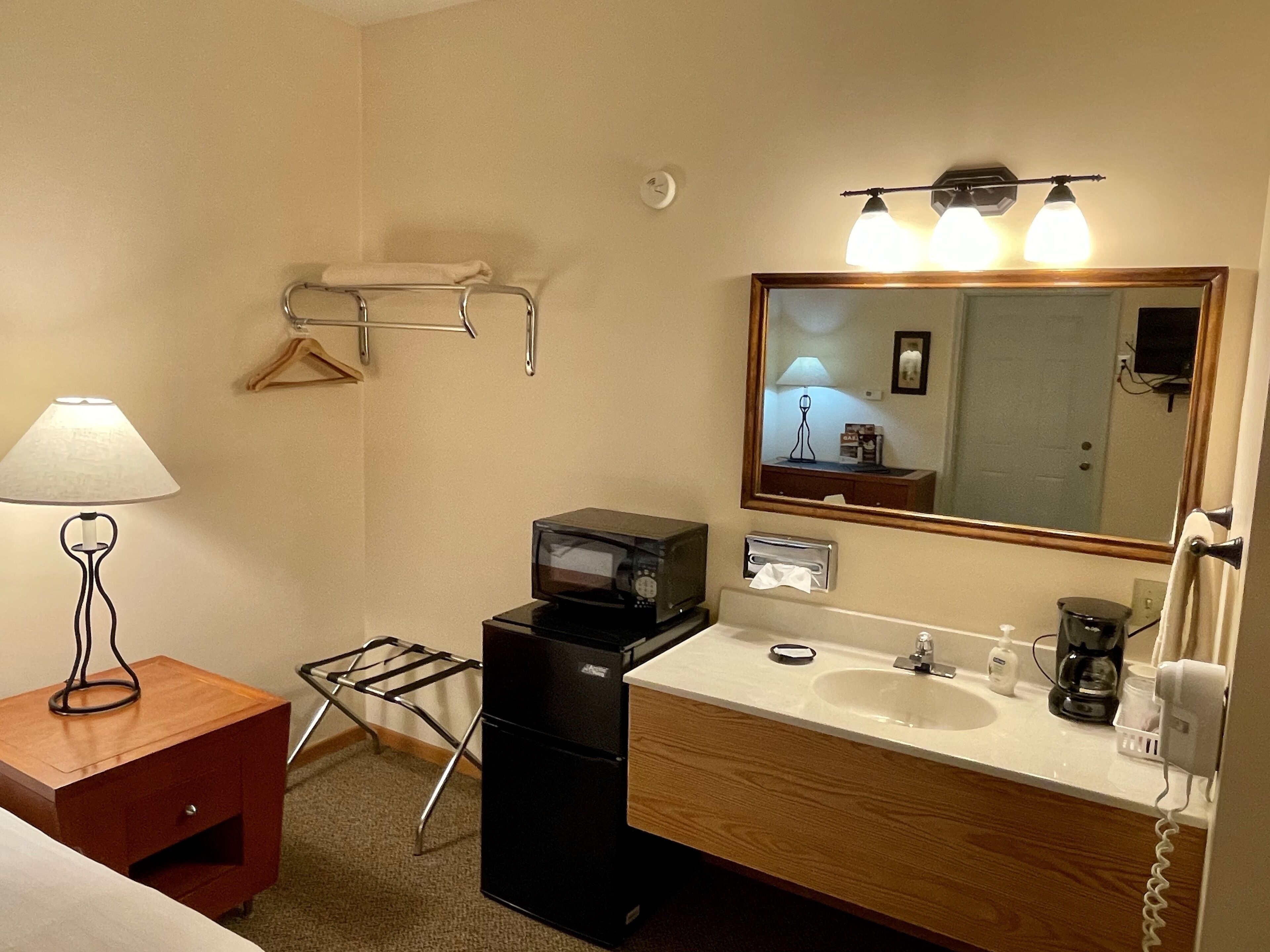 Een hotelbadkamer met een wastafel, spiegel, handdoekrek en een magnetron.