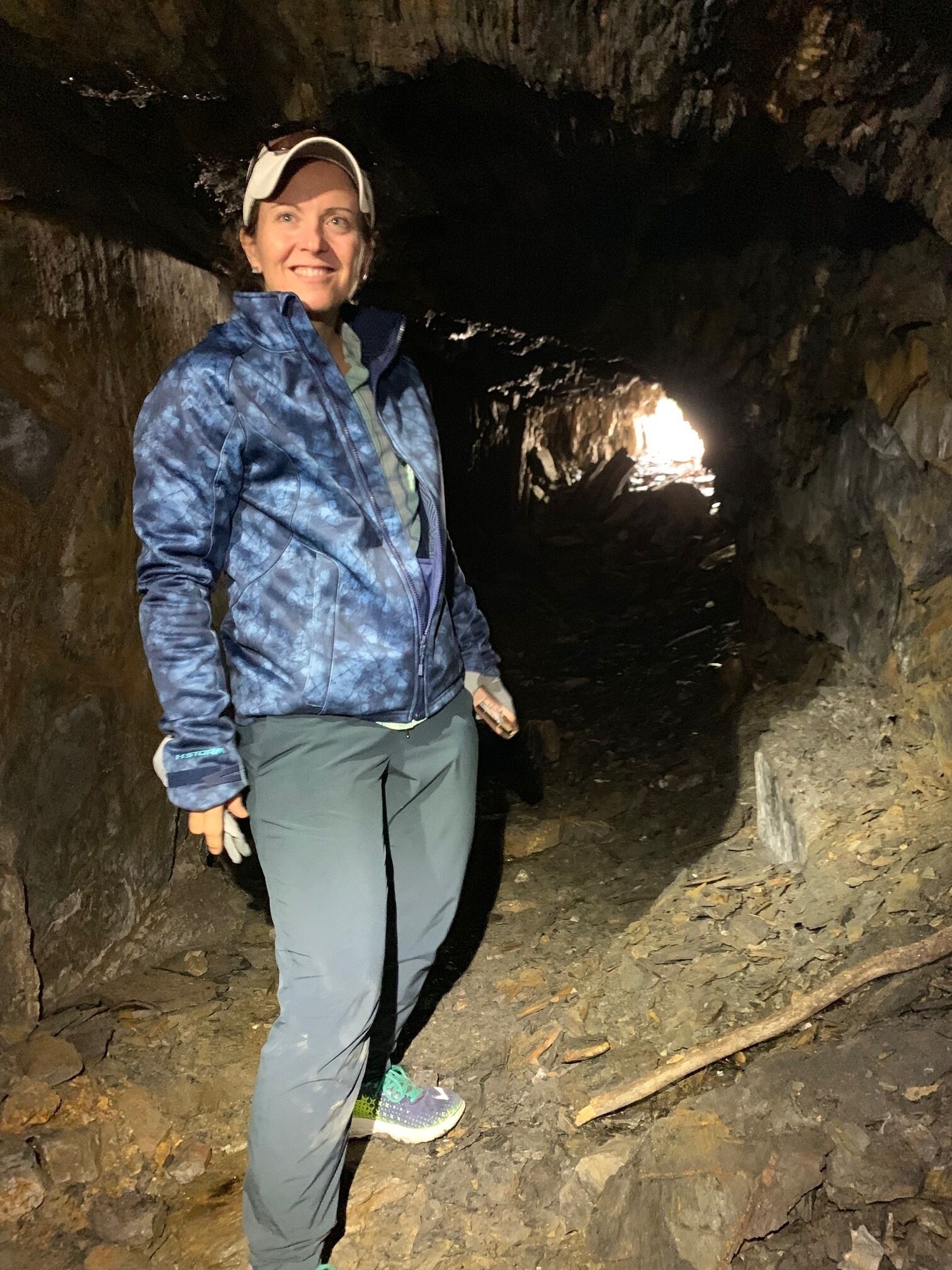 A person standing in a cave with rocky walls and a narrow passageway.