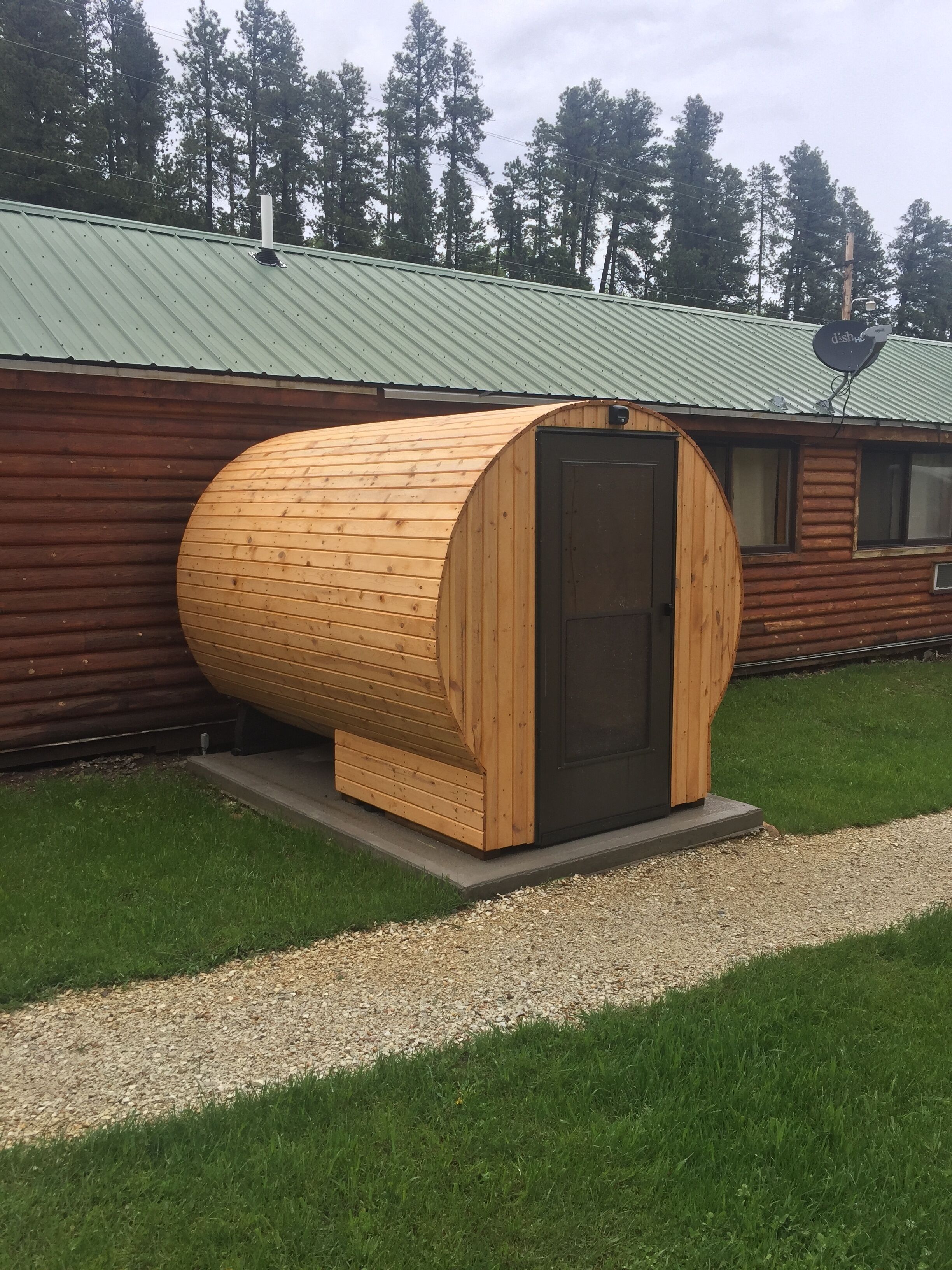 Una cabana de fusta amb una estructura cilíndrica gran, un teulat metàl·lic i un camí de grava que hi condueix.