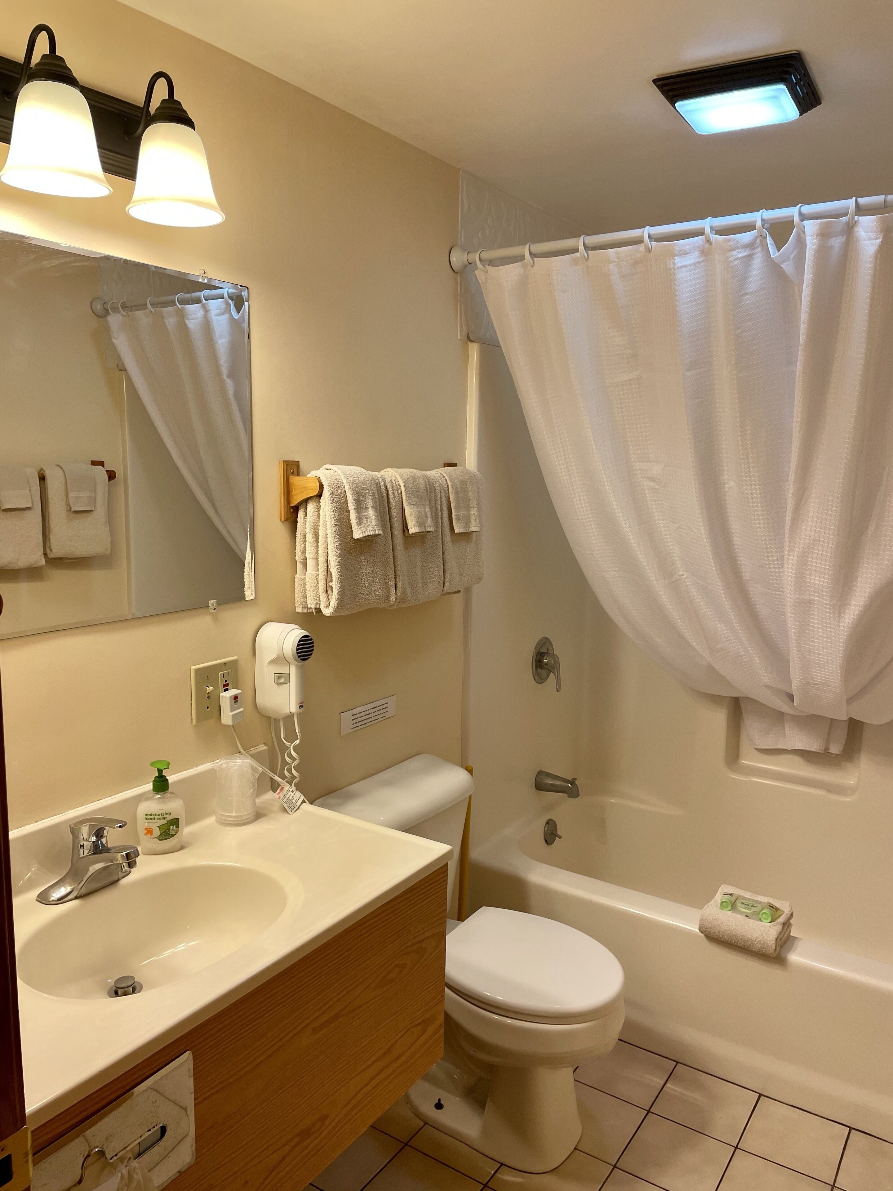 A bathroom with a sink, toilet, and bathtub. There are towels hanging on the wall and a shower curtain.