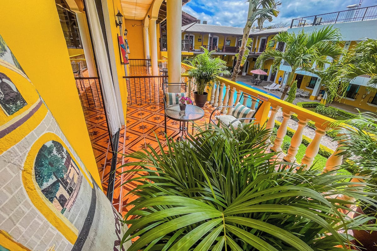 A balcony with a tiled floor, potted plants, and outdoor seating.