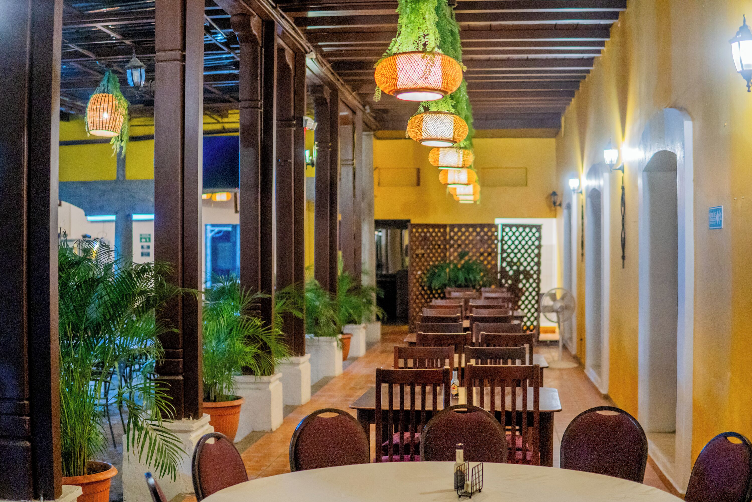 A restaurant with indoor seating, hanging lanterns, and potted plants.