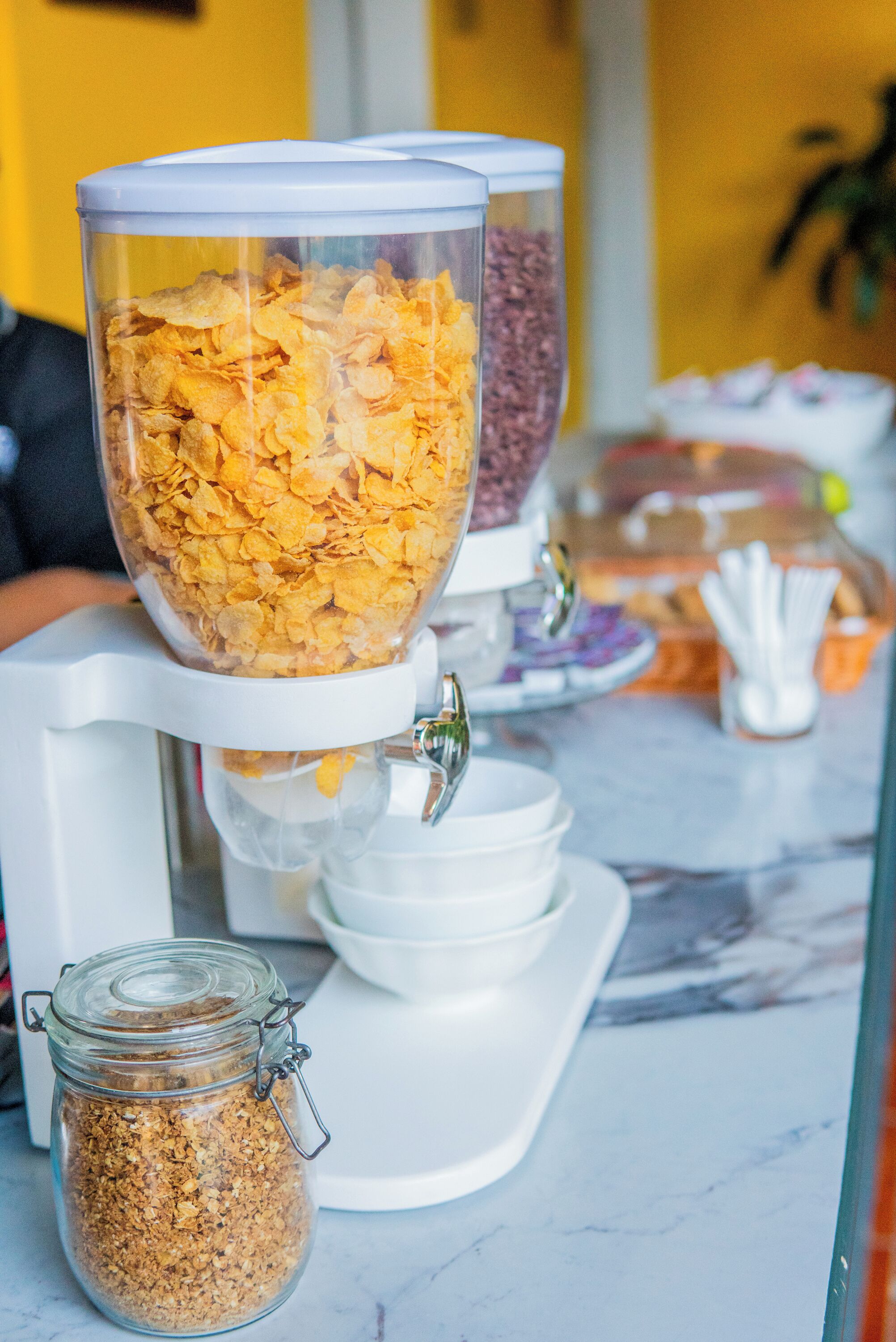 A breakfast buffet with cereal options in clear containers.