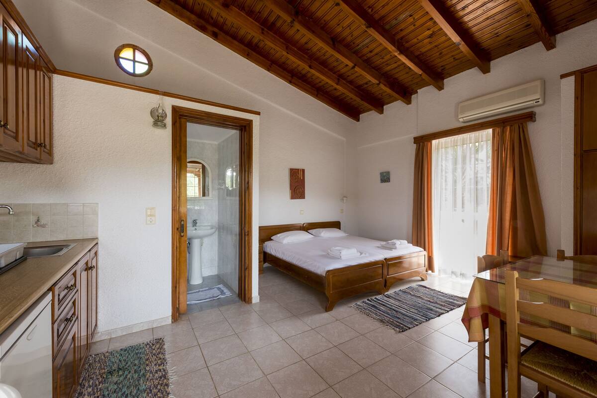 A bedroom with a wooden bed, a wooden table, and a window with curtains.