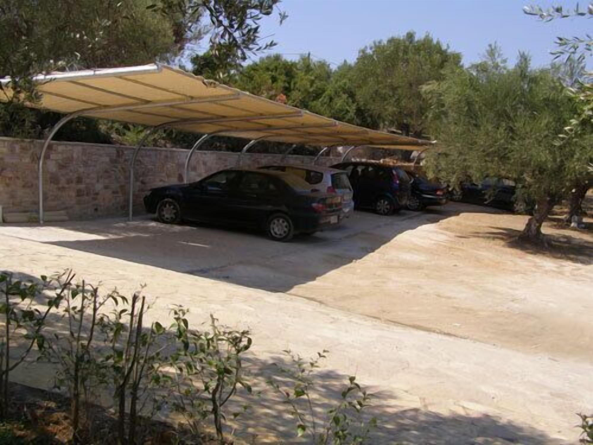Un área de estacionamiento con un toldo cubierto, un muro de piedra y automóviles estacionados.