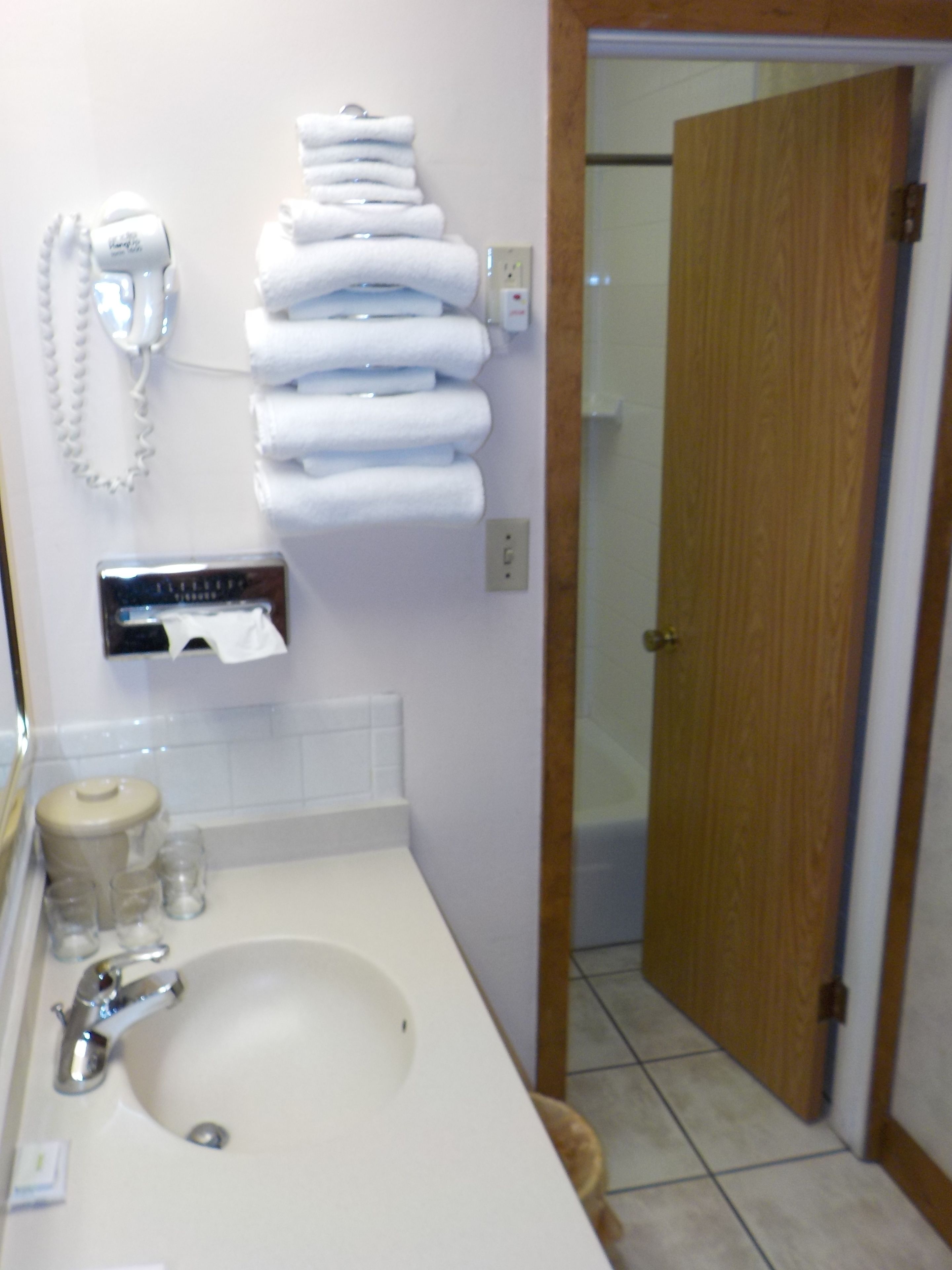 Een badkamer met een wastafel, een handdoekdispenser en een telefoon.