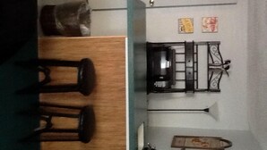 A room with a wooden table and chairs, a small kitchen area with a coffee maker, and a decorative item on the wall. - Hillside Cottages (Missouri Valley)