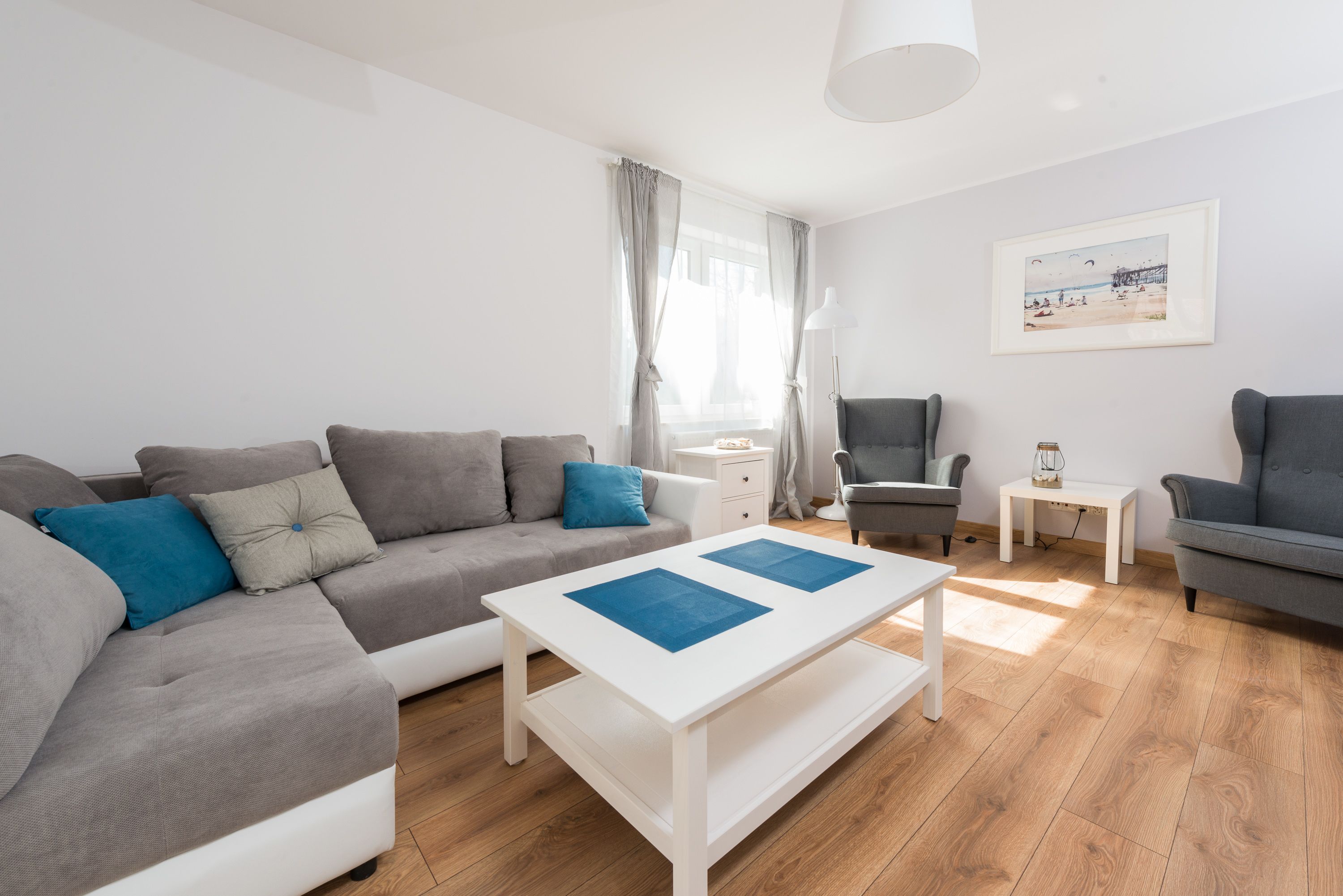 Ein modernes Wohnzimmer mit einem grauen Sofa, einem weißen Couchtisch und einem grauen Sessel.