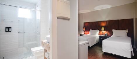 Ein Hotelzimmer mit Dusche, einem Bett, einem Nachttisch mit Lampen und Holzboden.