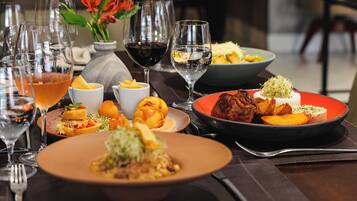 A table set with various dishes, glasses of wine, and a vase with flowers.