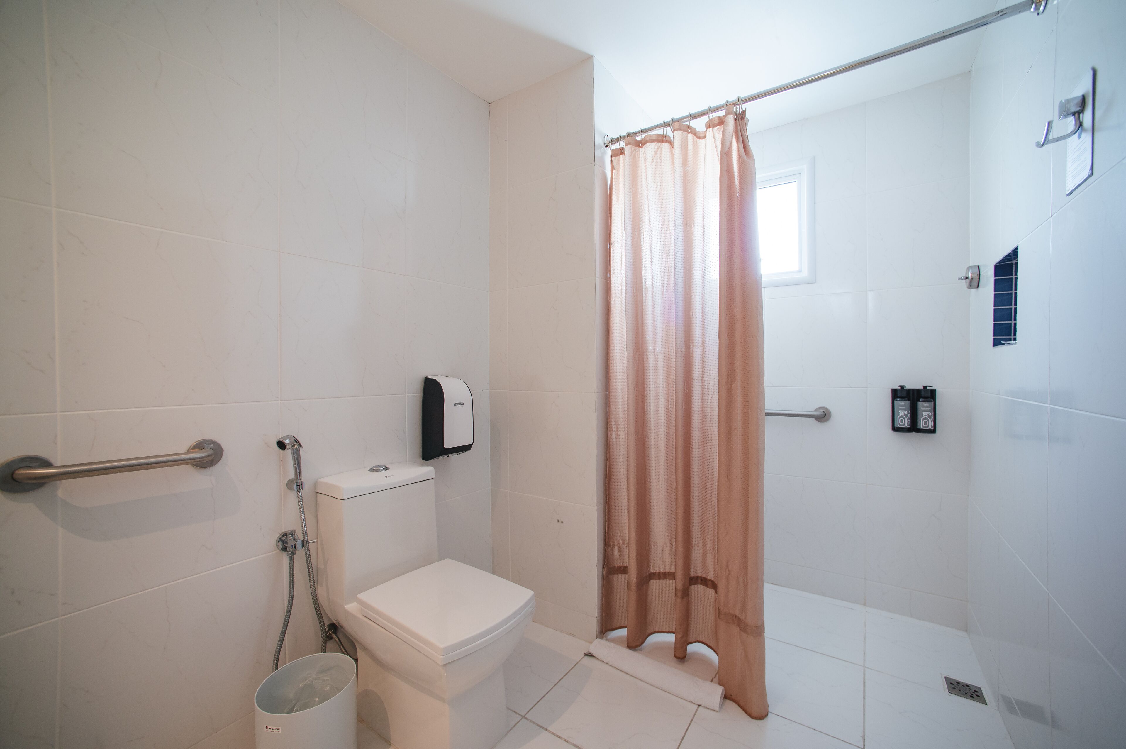 A bathroom with a toilet, a shower, and a hand dryer.