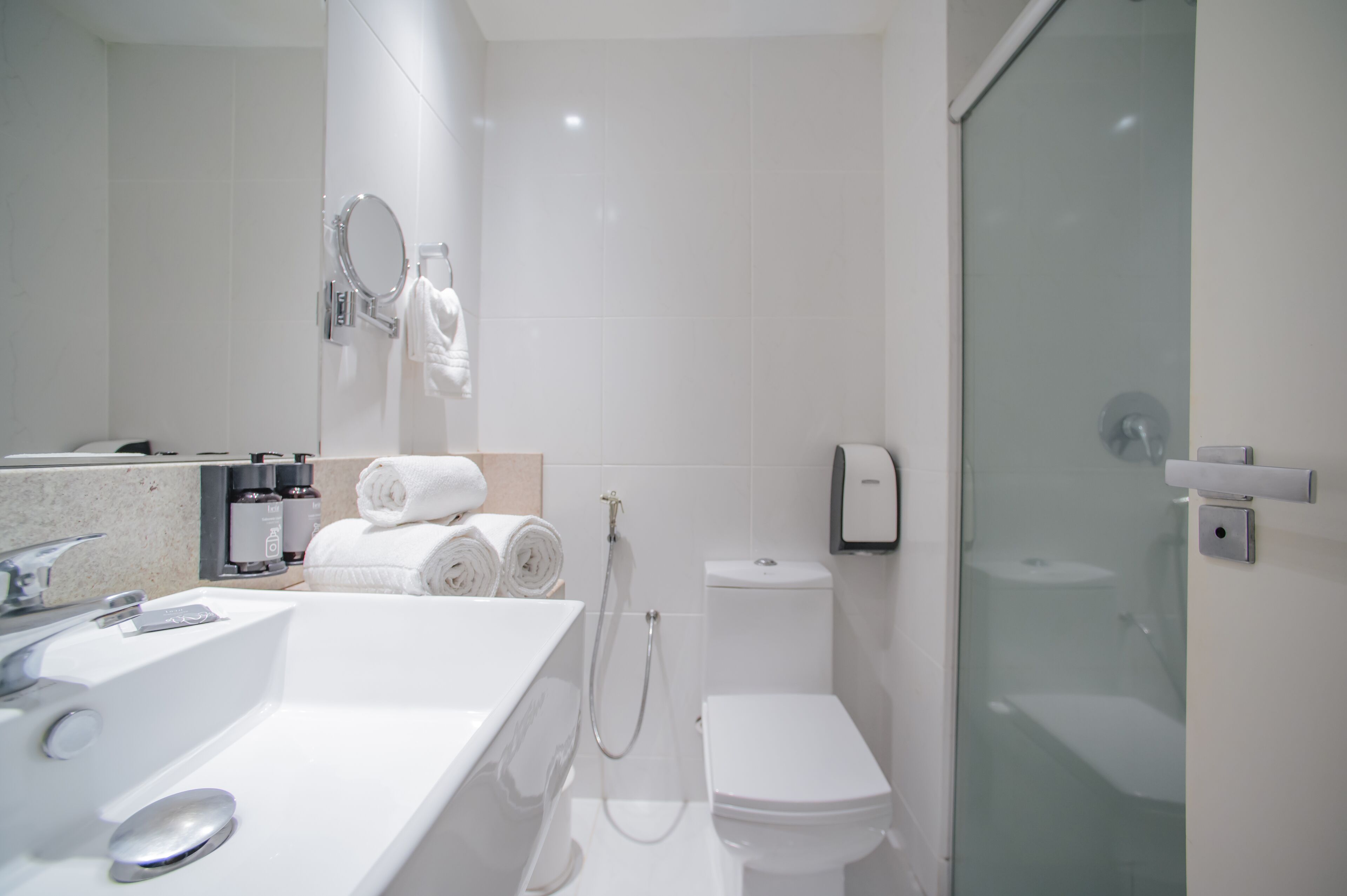 Een moderne badkamer met een groot wastafel, toilet en een douchecabine met glazen wanden.