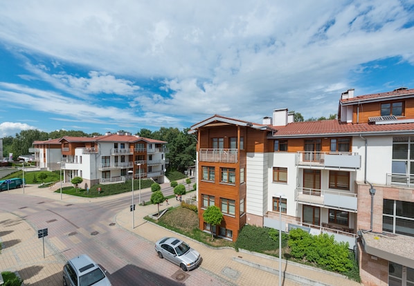 A modern residential building with multiple balconies and a parking area.