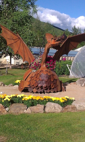 Eine Drachenskulptur, umgeben von Blumen und Steinen.