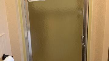 A bathroom with a glass shower door, a white towel hanging on the wall, and a visible towel rack.