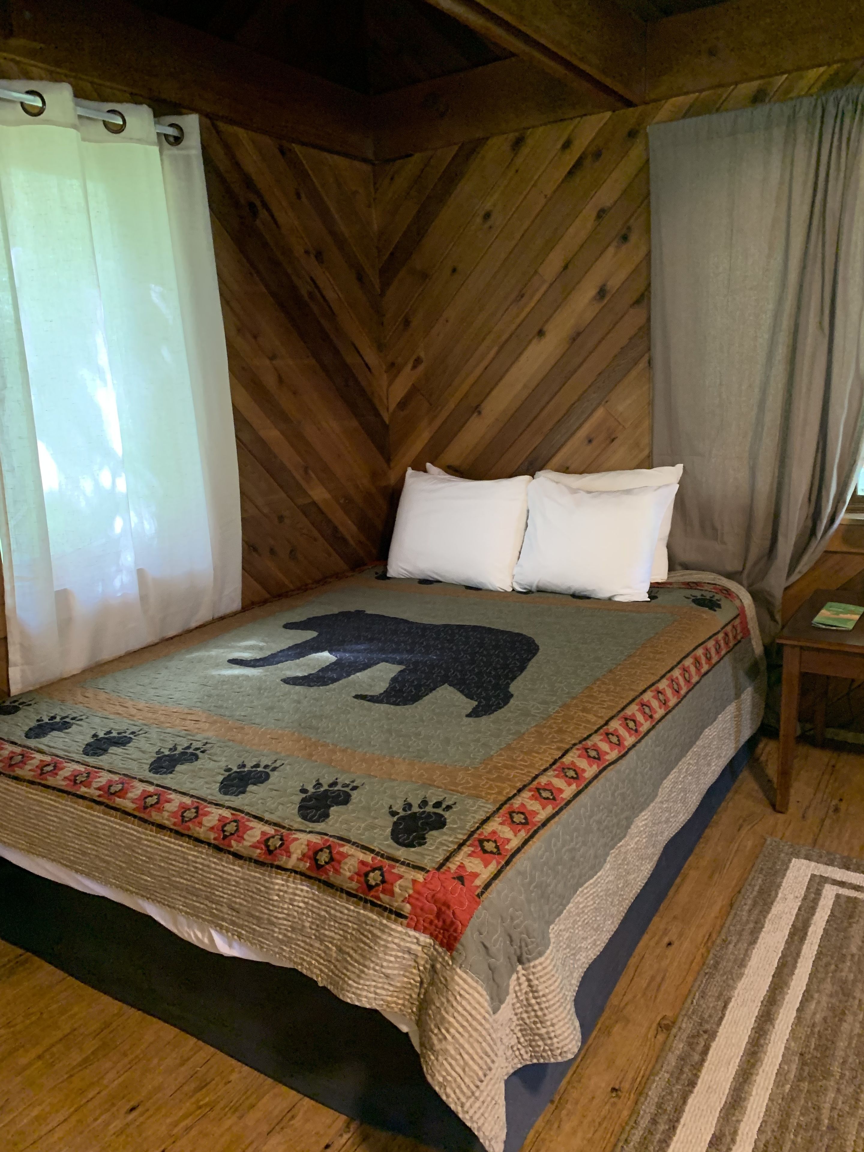 Een kamer met houten lambrisering, een bed met een bergleeuw dessin en pootafdrukken.