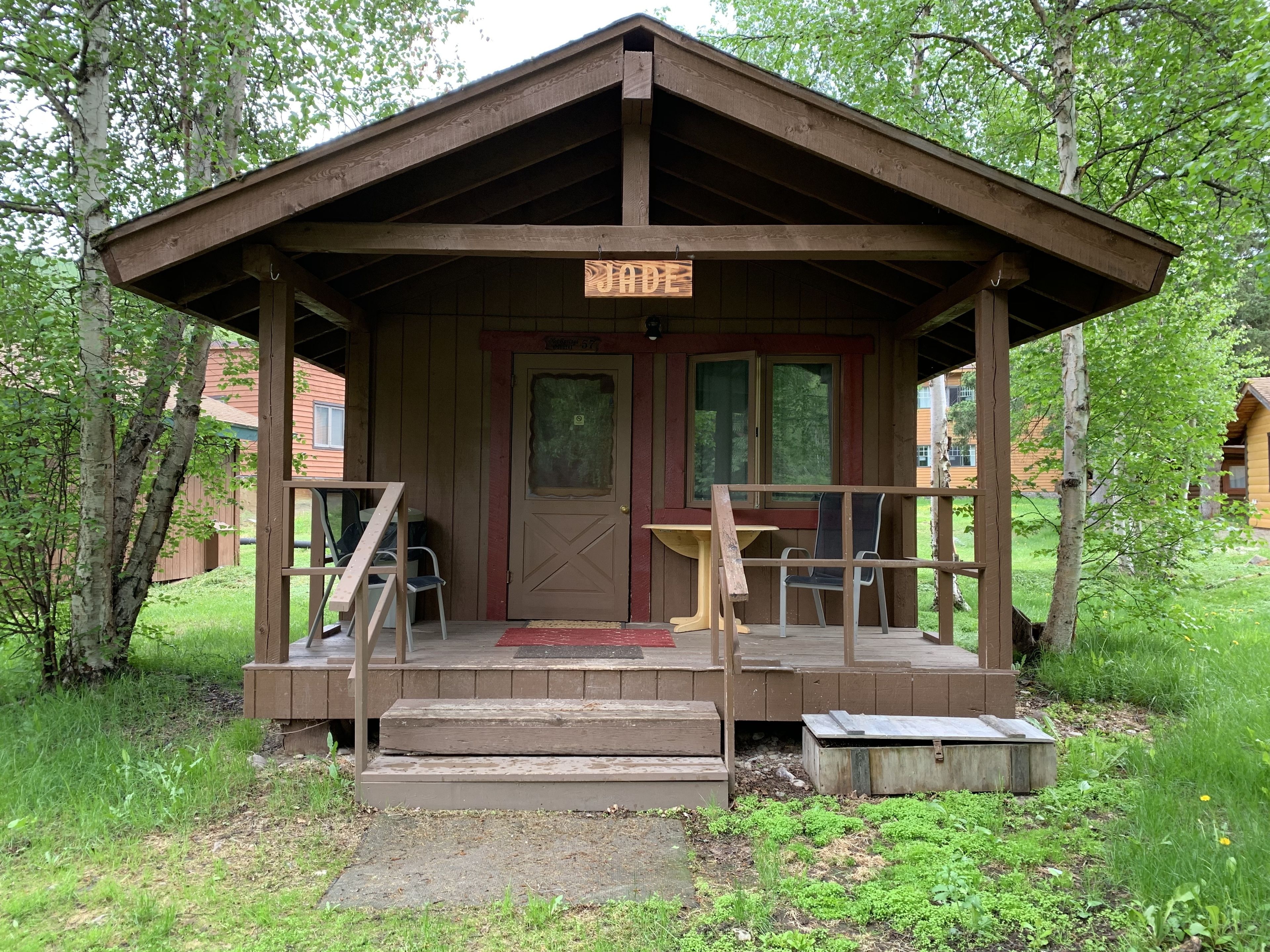 A wooden cabin with a porch, a door, and a sign above the door.