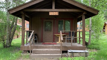 A wooden cabin with a porch, a door, and a sign above the door.