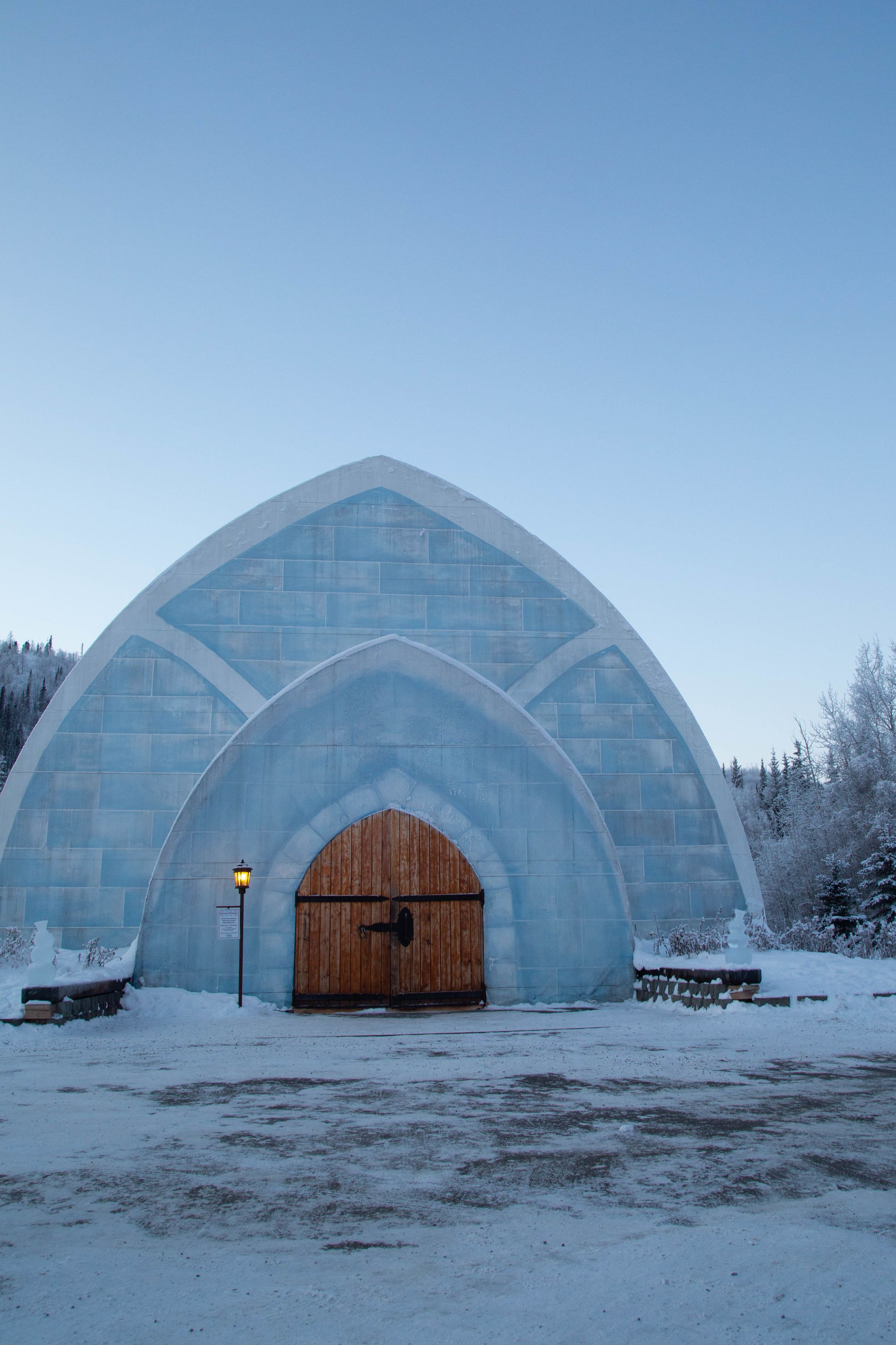 A large, arched building with a wooden door, surrounded by snow.