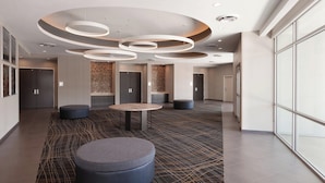 A modern lobby with a circular ceiling design, a central seating area, and a patterned carpet. - SpringHill Suites by Marriott Houston Northwest (Houston)