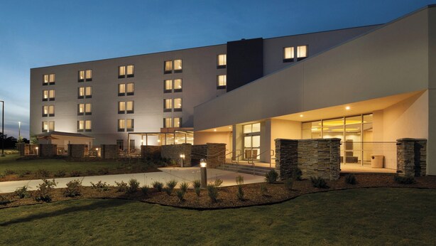 A modern hotel with a flat roof, multiple windows, and a well-lit entrance. - SpringHill Suites by Marriott Houston Northwest (Houston)