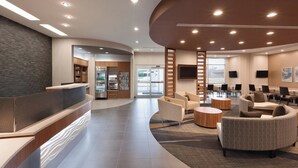 A modern lobby with a curved reception desk, seating area, and a view of the entrance. - SpringHill Suites by Marriott Houston Northwest (Houston)
