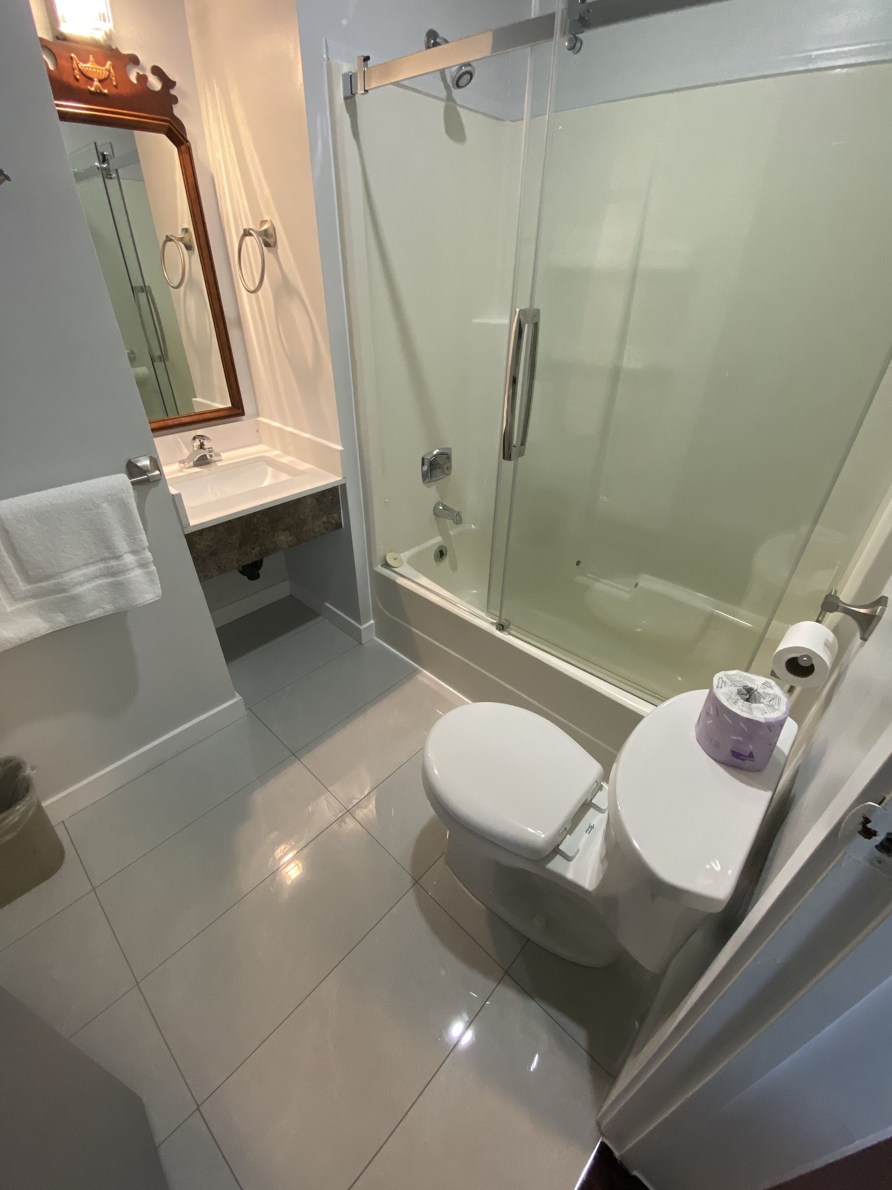 Un baño moderno con ducha envuelta en vidrio, lavamanos blanco y un inodoro.