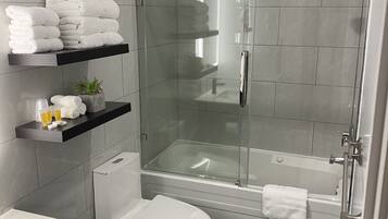 Une salle de bain moderne dotée d’une douche à parois de verre, de toilettes et d’un lavabo.