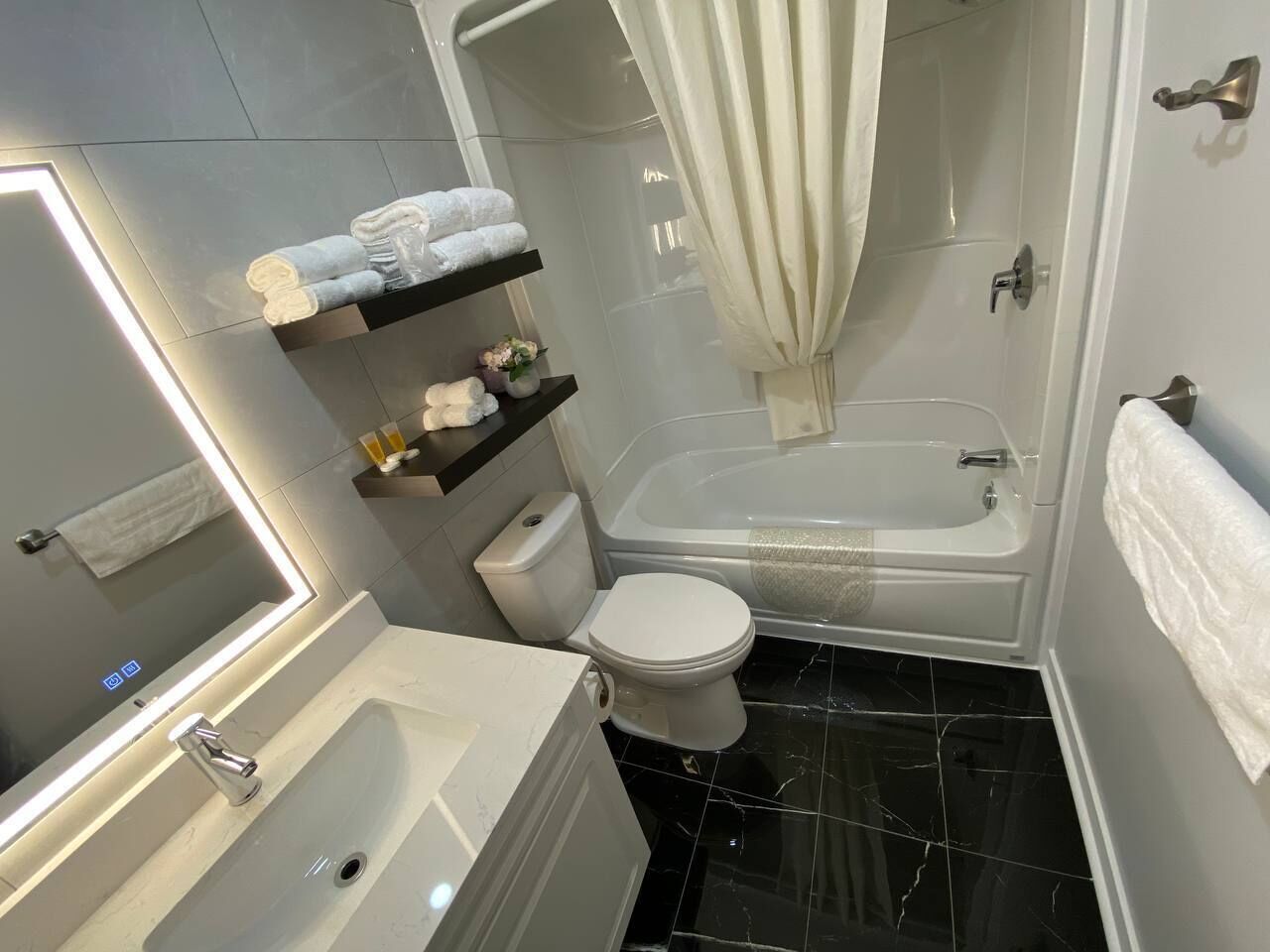 A modern bathroom with a bathtub, toilet, and a vanity with a mirror.